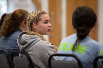 Three teenage girls sitting with their back to the camera.