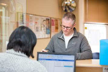 A man with glasses standing at a doctor's reception desk