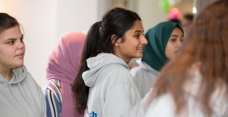 Three young girls wearing grey hoodies looking to the right of the camera