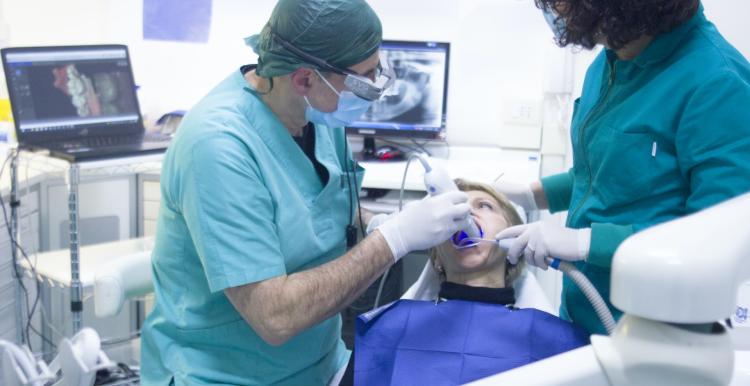 someone sitting in a dentist chair with a dentist next to them, surrounded by dental tools and equipment