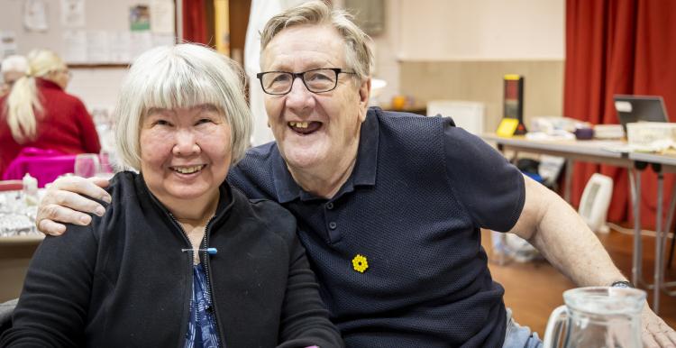 An older women and man sitting at a table smiling to the camera