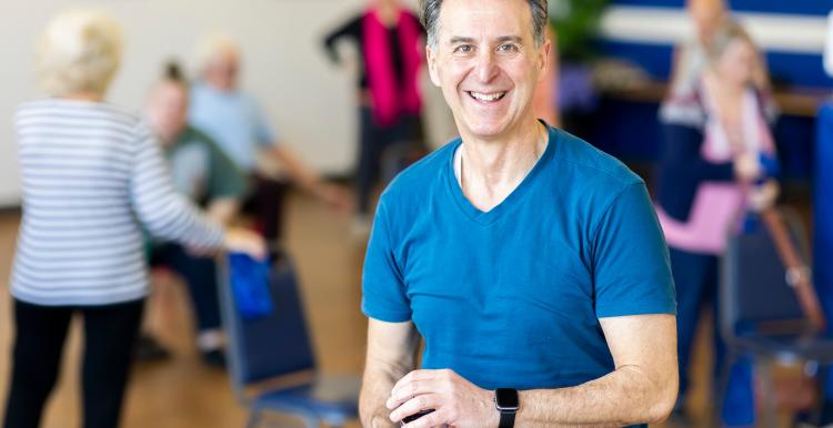 A man in a blue t shirt smiles at the camera