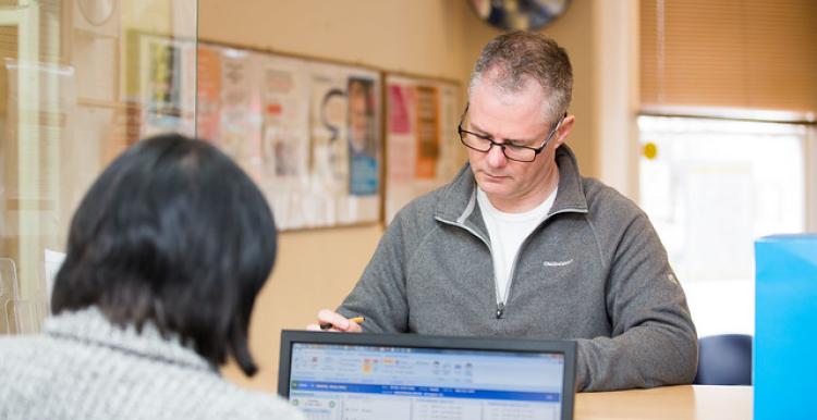 A man with glasses standing at a doctor's reception desk