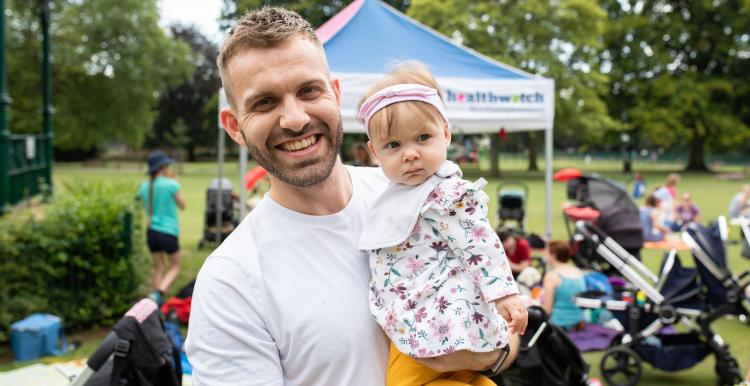 Man holding a baby outside and smiling