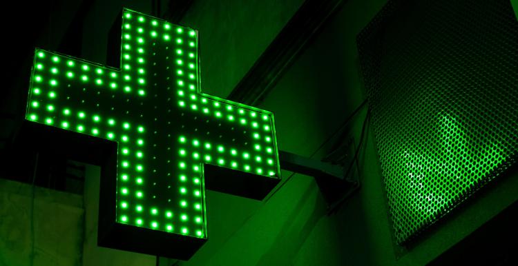 A bright green luminous pharmacy cross