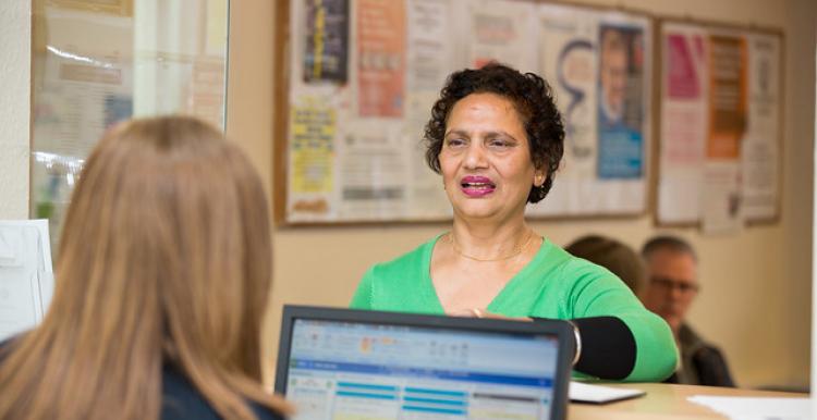 A woman stands at a hospital reception desk 