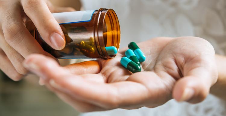 A close up of hands holding a medicine bottle