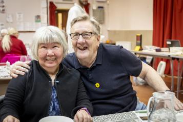 An older women and man sitting at a table smiling to the camera