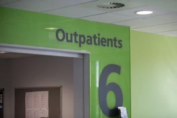 A green wall with a large number 6 and a sign that reads Outpatients