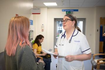 A woman patient talking to a nurse in a waiting room 