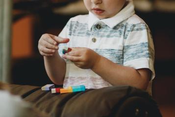 A pre-school aged boy sits and plays lego